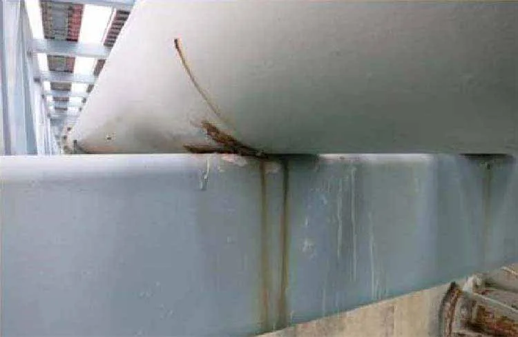 an image of a pipe resting on a steel pipe support in an industrial pipe rack that has corrosion build up at the point of where the pipe is resting on the support