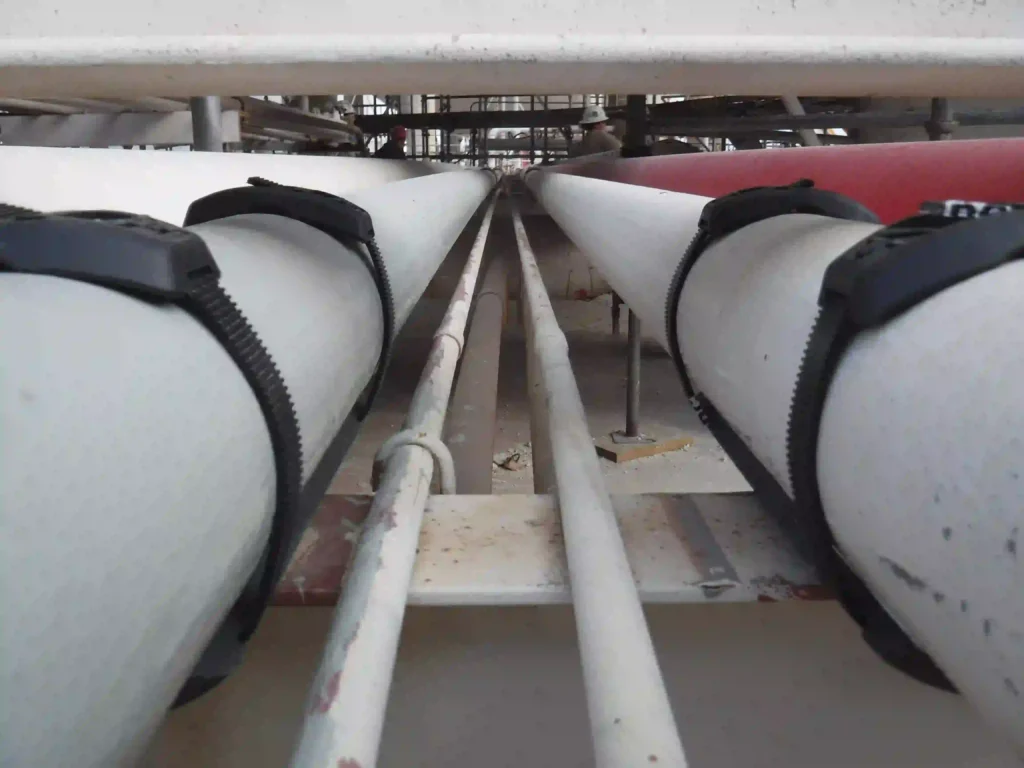 SmartPad pipe support system installed on parallel painted pipes above a steel support platform in an industrial facility